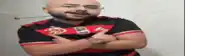 a bald man with a beard is wearing a red and black shirt with the letter r on it
