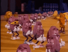 a bunch of cartoon characters are dancing on a wooden floor and one of them is giving a thumbs up .