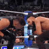 two wrestlers in a wrestling ring with the letter w on the corner
