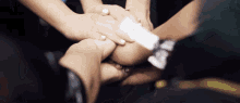 a group of people putting their hands together with a white piece of paper in the middle