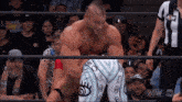 a man is wrestling another man in a wrestling ring while a referee looks on .