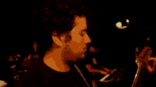 a close up of a man 's face in a dark room looking down at something .