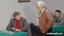two men are sitting at tables talking to each other .