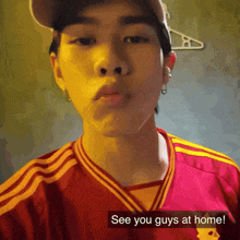 a man wearing a red and yellow shirt with the words see you guys at home on the bottom