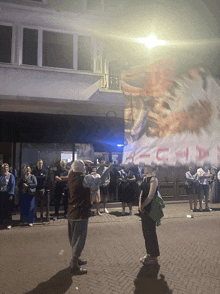 a group of people standing in front of a building with a sign that says ' s.h.p. '