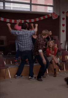 a group of people are dancing in a room with hearts hanging from the ceiling