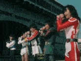 a group of people are standing next to each other in front of a building and one of them is holding a microphone .