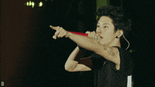 a man with a tattoo on his arm is singing into a red microphone