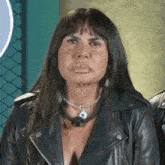 a woman wearing a leather jacket and a necklace is making a face .