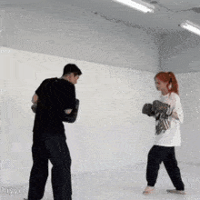 a man and a woman are boxing in a gym and the woman is wearing a white shirt that says hiyyil