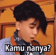 a young man wearing a bandana and a denim jacket is making a funny face with the words kamu nanya .