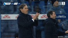 a man applauds in front of a sign that says eyesportwear.com on it