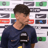 a man in a laliga shirt stands in front of a laliga tv microphone