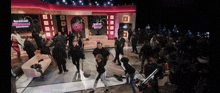 a group of people are dancing on a stage in front of a sign that says baddie highness reunion