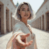 a woman in a white dress reaches out her hand towards the camera