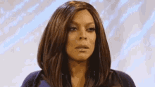 a woman with long brown hair is wearing a wig and making a funny face .