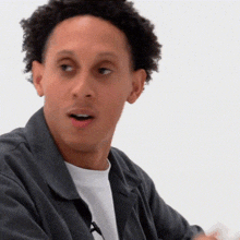 a man with curly hair and a white shirt is making a funny face .