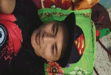 a man wearing a superman hat is laying on a pillow .