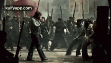 a man is walking in front of a crowd of people with guns .