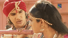 a man and a woman are looking at each other with a sony television ad behind them