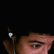 a man wearing ear buds is crying with a tear coming out of his eye .