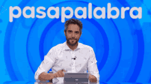 a man sitting in front of a blue background with the word pasapalabra on it