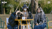 three people are sitting around a table with a number 3 on it
