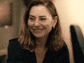 a woman in a black shirt and hoop earrings smiles