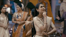 a woman in a white dress is standing in front of a group of women in traditional clothes .