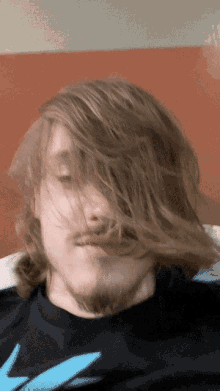 a man with long hair and a beard wearing a black shirt with a blue shark on it