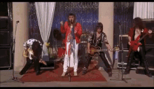 a group of people are standing on a stage playing instruments and singing into microphones .