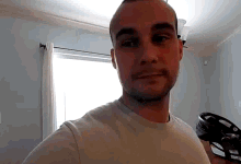 a man with a beard wearing a white shirt looks at the camera