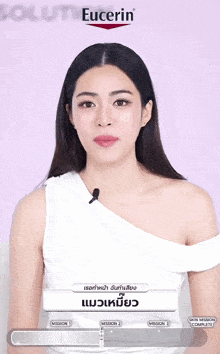 a woman wearing a white off the shoulder top is talking into a microphone in front of a eucerin sign