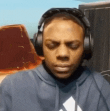 a man wearing headphones and a hoodie with an adidas logo on it
