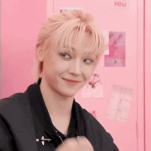 a boy with blonde hair is making a funny face in front of a pink locker .