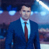 a man in a suit and tie is standing in front of a blurry background .