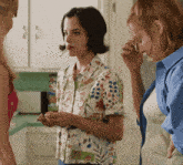 a woman in a floral shirt is smoking a cigarette in a kitchen