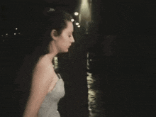 a woman in a dress is walking down a street at night .
