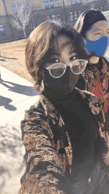 a woman wearing glasses and a mask is taking a selfie