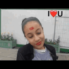 a girl with red lipstick on her forehead and the words i love u above her