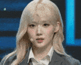 a woman with blonde hair is wearing a gray suit and white shirt