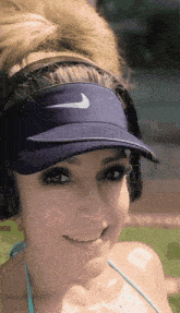 a woman wearing a nike visor and headphones smiles for the camera