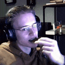 a man wearing headphones and glasses eating a piece of food