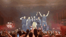 a group of people on stage with their arms in the air