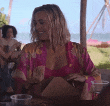 a woman in a pink robe is sitting at a table