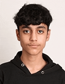 a young boy wearing a black hoodie is looking at the camera .