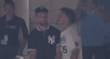 a man wearing a ny yankees shirt talks to another man