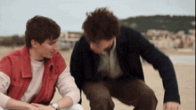 two men are sitting on the beach and one of them is wearing a watch
