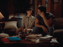a man and a woman are sitting on a couch looking at something