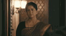 a woman wearing a pearl necklace is standing in a room